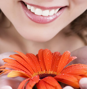 A woman smiling next to a flower